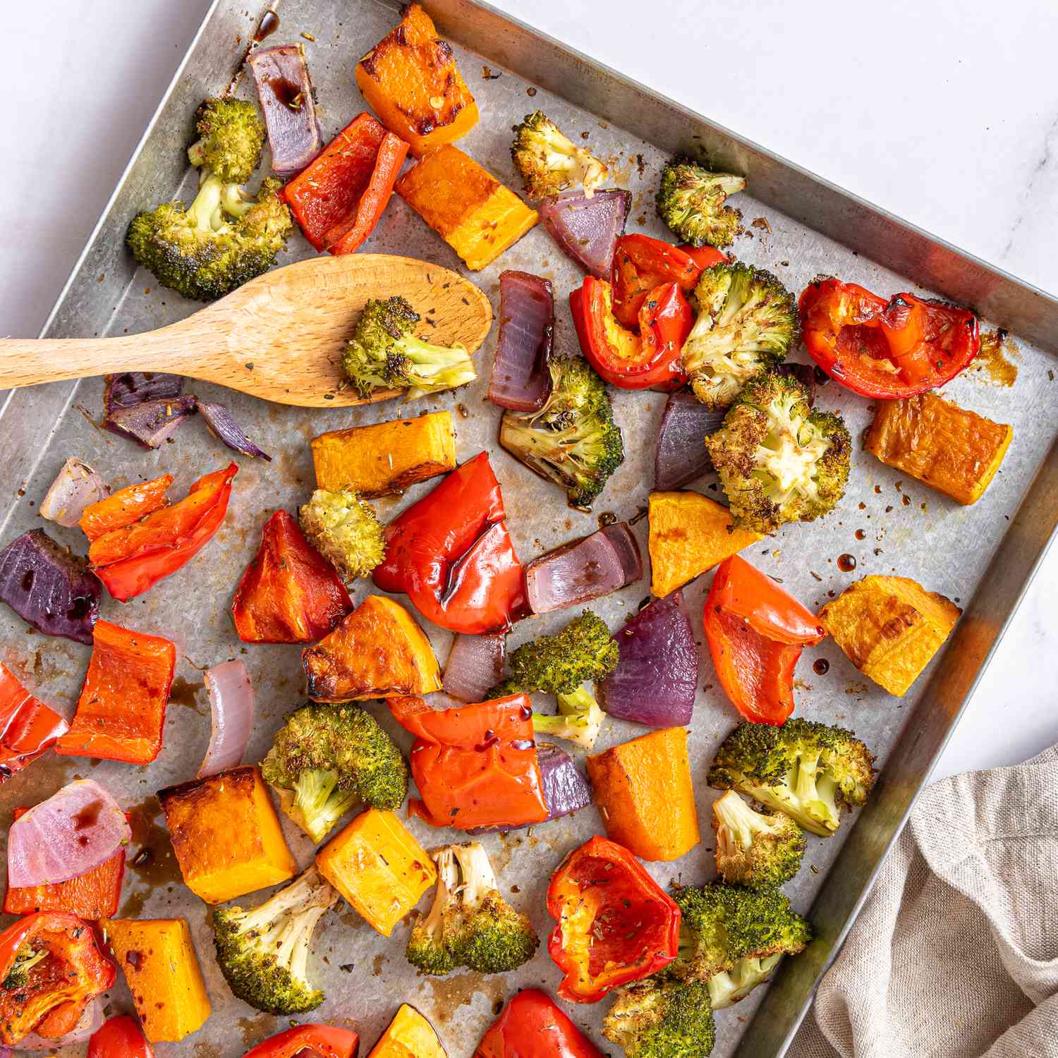 Foto de receta fotográfica de coloridas verduras asadas dispuestas en una bandeja para hornear galletas