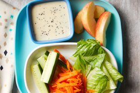 Foto de ensalada infantil con verduras, frutas y salsas para mojar.