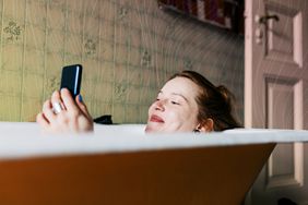 Una mujer que envía un correo electrónico con una sonrisa mientras se baña