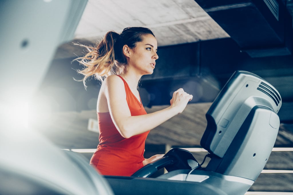 Mujer joven sana corriendo en una cinta de correr en el gimnasio